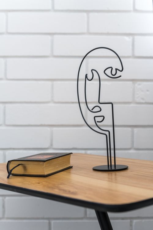 Free Abstract metal sculpture and book on a wooden table against a brick wall. Stock Photo