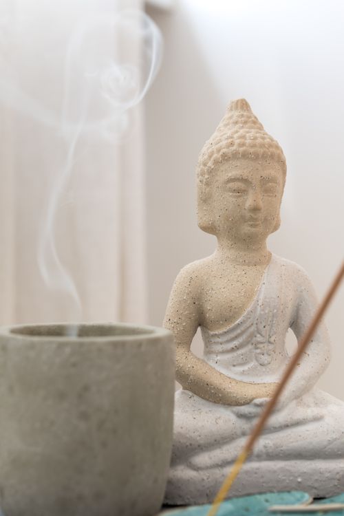 Free Close-up of a Buddha figurine with incense smoke in a calming indoor setting. Stock Photo