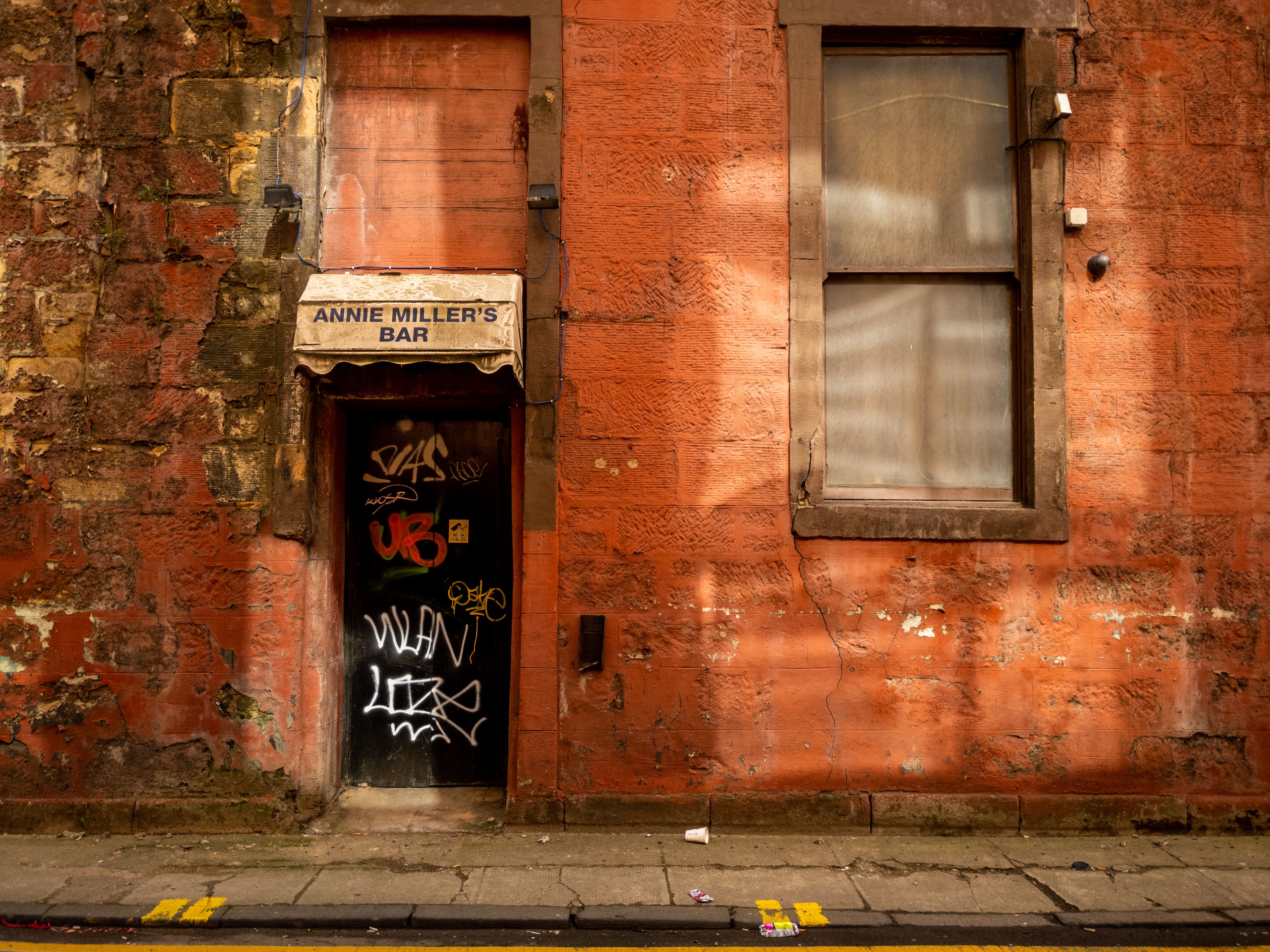 grungy city street with a red bar door at night