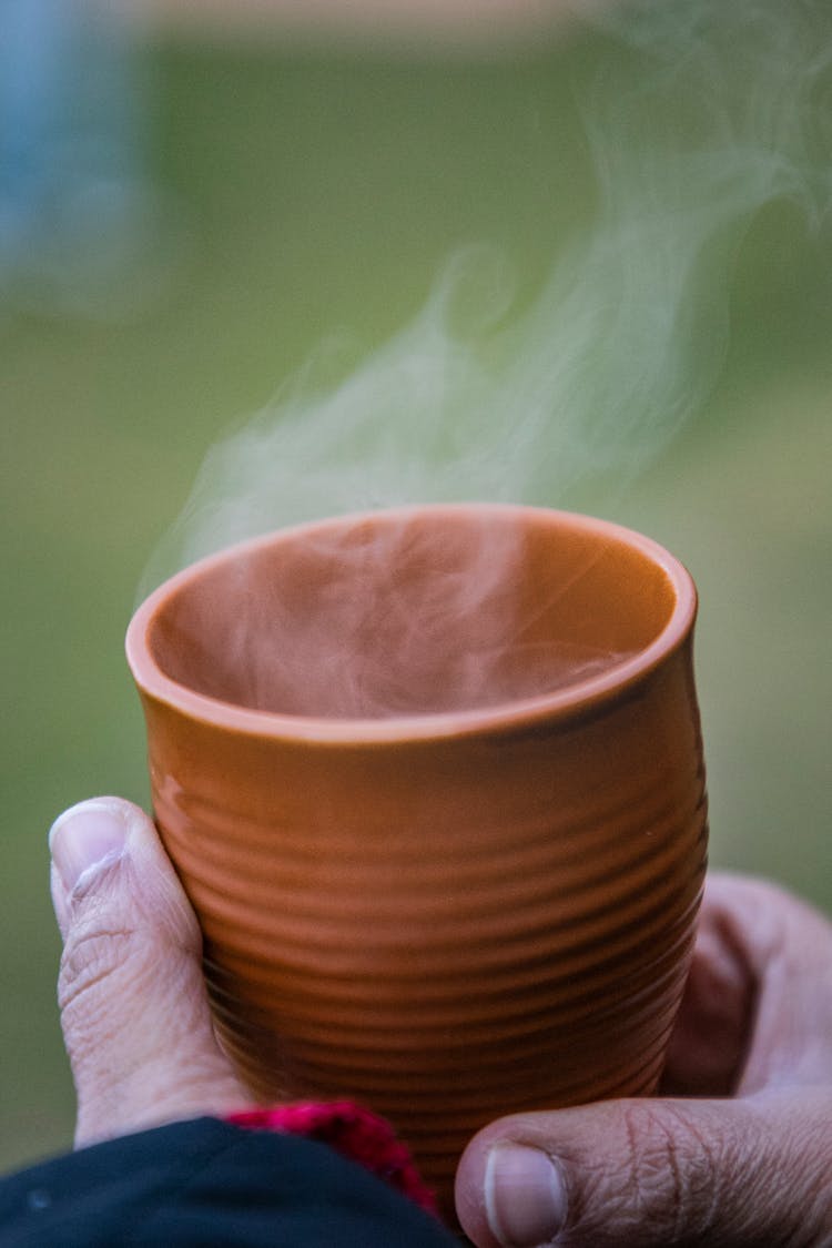 A Person Holding A Steaming Cup