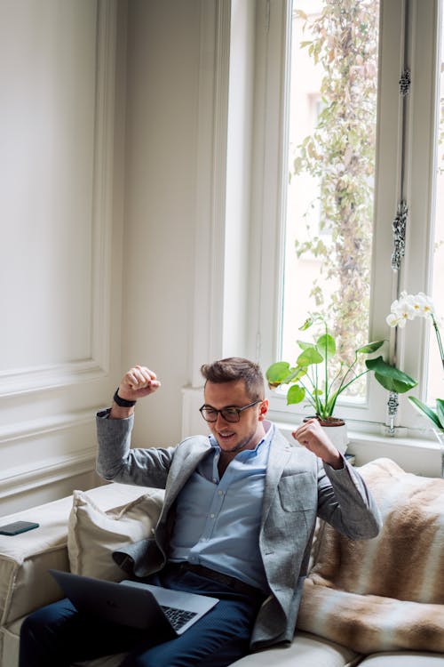 Free Happy Man Sitting with Laptop Clenching Fists Stock Photo