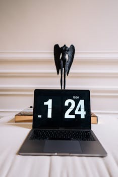 Elegant desk setup with a laptop displaying time and a unique sculpture in an airy home office.