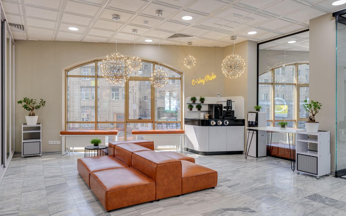 Spacious modern office lobby featuring leather seating, a coffee station, and elegant lighting.