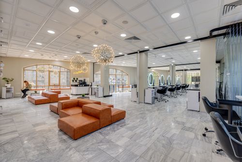 Free Spacious salon interior with leather seating, marble floor, and decorative lighting, offering a stylish ambiance. Stock Photo
