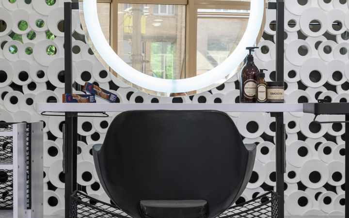 A stylish salon workstation featuring a ring light mirror and sleek black chair.