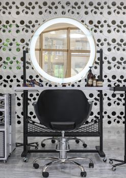 A stylish salon workstation featuring a ring light mirror and sleek black chair.