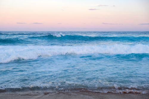 Free Peaceful seascape with gentle waves under a pastel sky at sunrise. Stock Photo