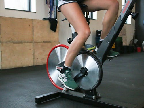 Person exercising on cycling machine in gym