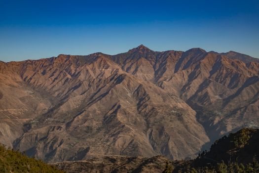 Breathtaking aerial view of the rugged mountain peaks near Mussoorie, India under clear blue skies.
