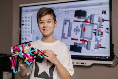 Boy in White Crew Neck T-shirt Holding a Plastic Robot Project