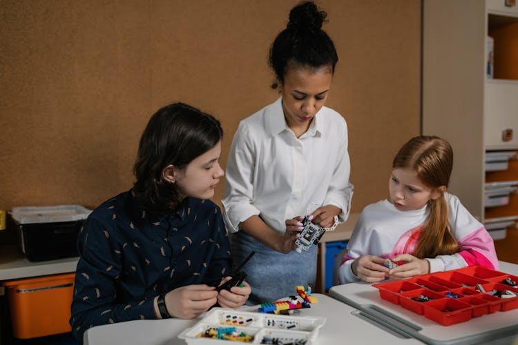 A Woman Standing Between A Young Man And A Girl Holding Gray Lego Piece