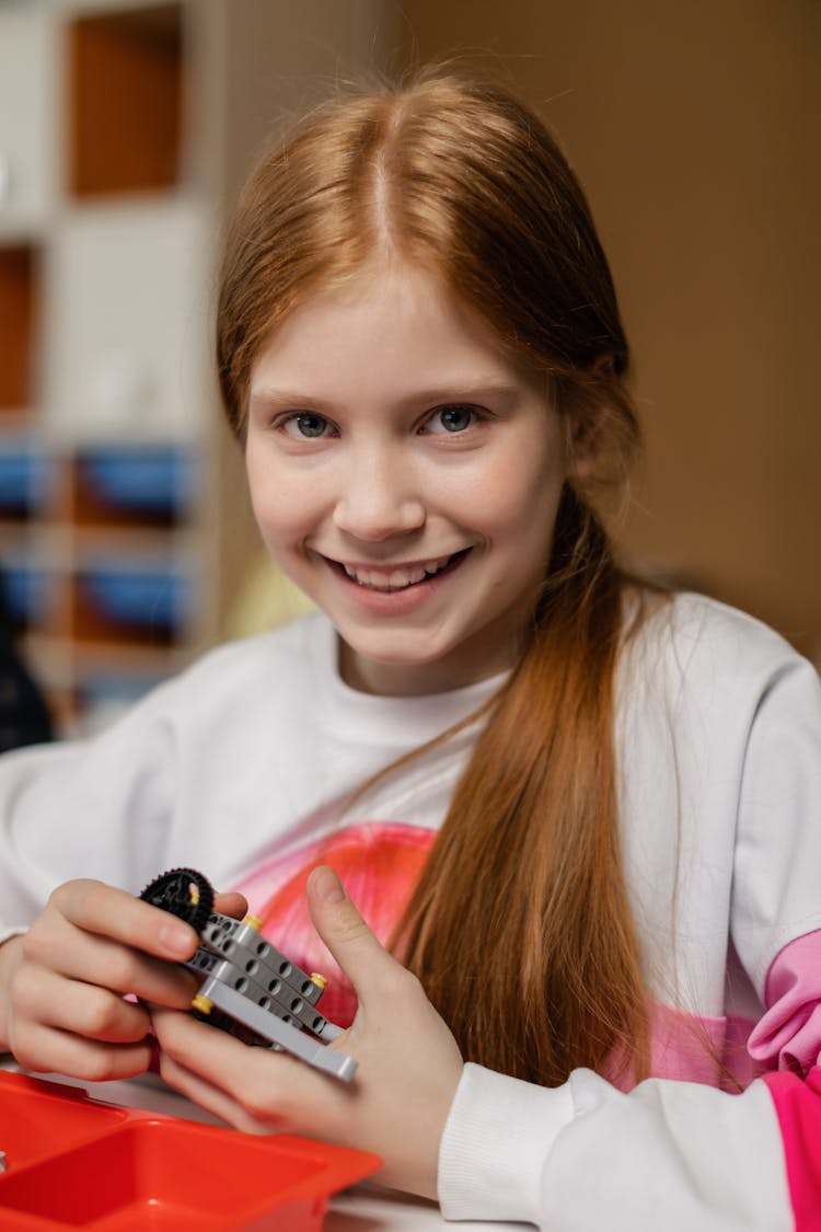 A Girl Holding Gray Lego Piece