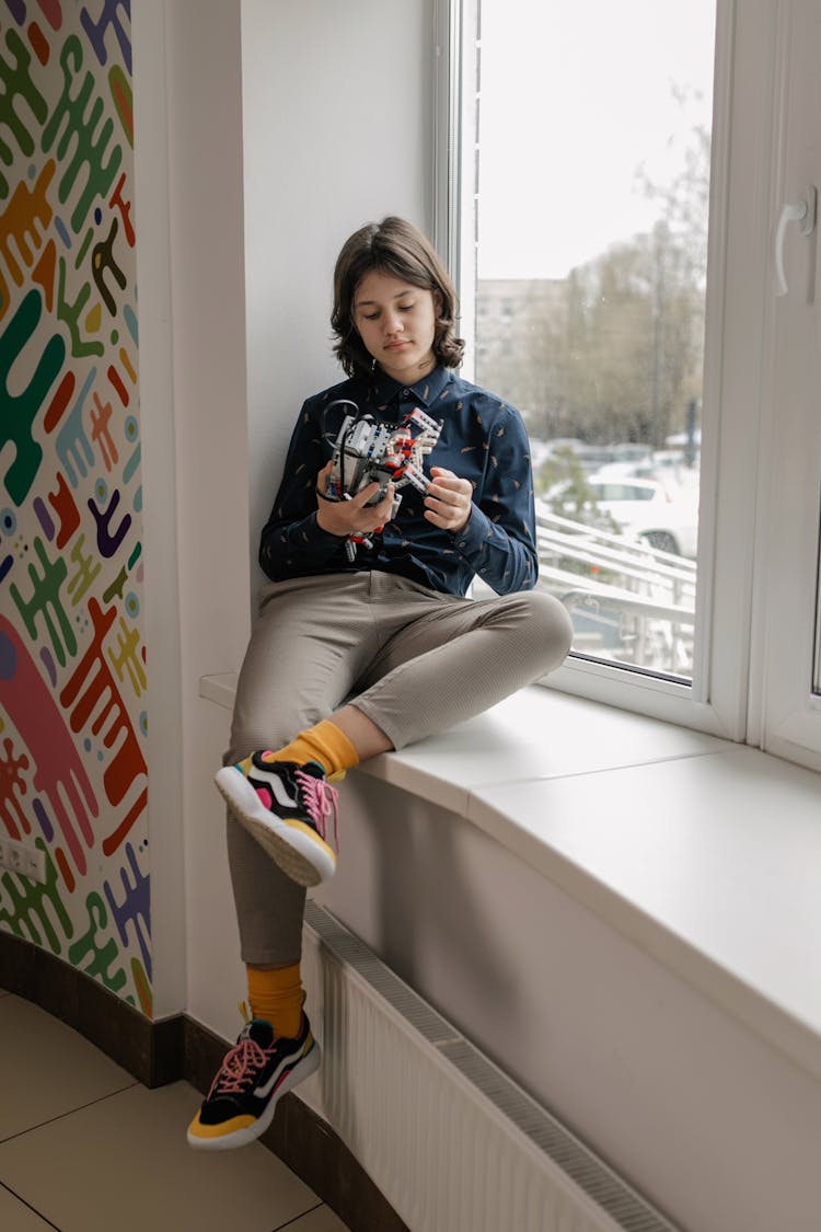 A Kid Sitting By A Window