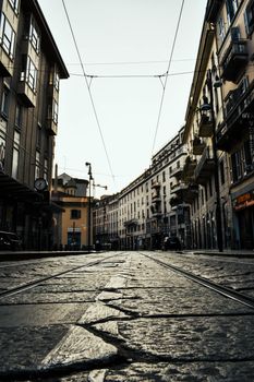 Low angle view of a quiet Italian street with historic buildings and cobblestone pavement.
