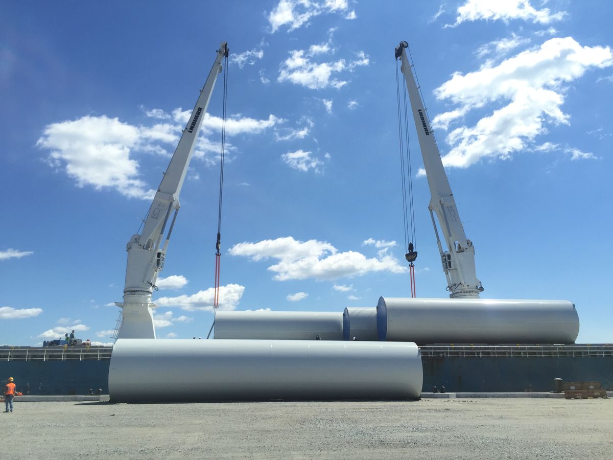 Cranes lifting large wind turbine blades at a port