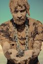 Man with chain on neck covered with clay