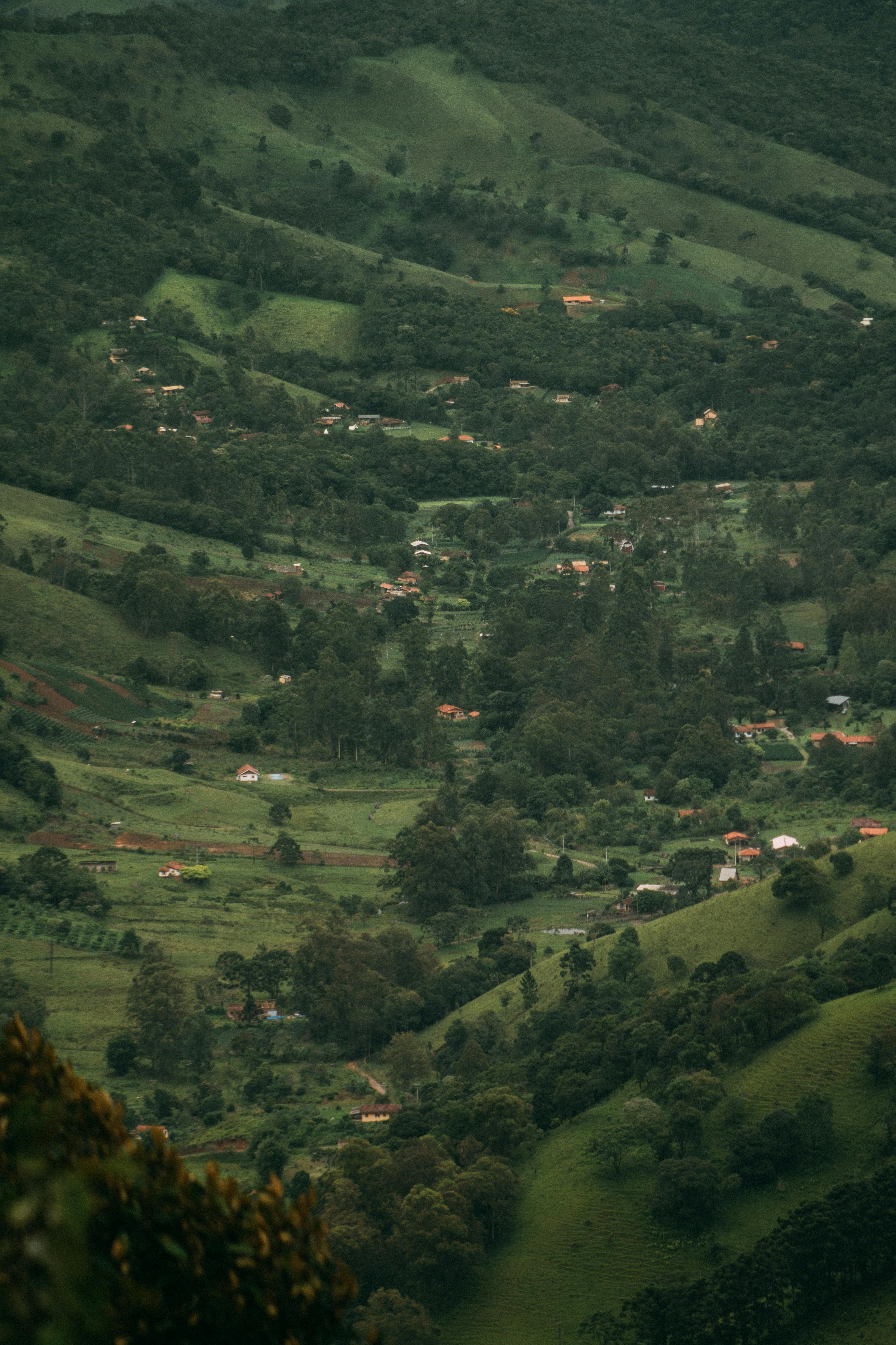Aerial view of a picturesque valley with lush greenery and scattered houses, showcasing natural beauty and rural life.