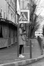 Woman Standing on City Sidewalk Near the Street Sign