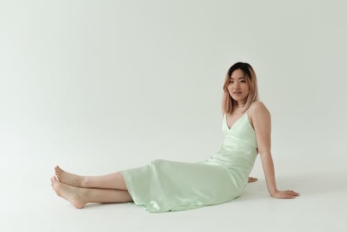 A Pretty Woman Wearing a Green Dress Sitting on the Floor