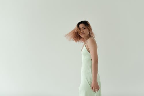 Woman in a Light Green Dress Flipping Her Hair while Looking at the Camera