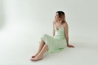 Woman in Green Sleeveless Dress Sitting on White Floor