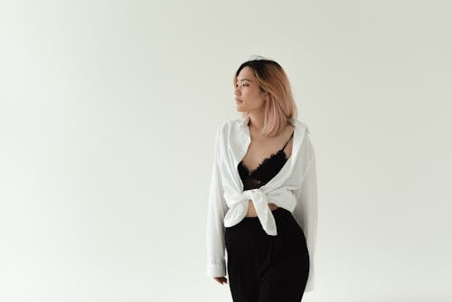 A Woman in White Long Sleeves with Black Bralette Standing while Looking Over Shoulder