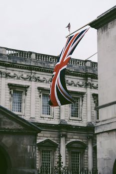Union Jack flag hanging from a historic building facade in Somerset House, London, UK.