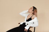 Woman in White Long Sleeve Shirt and Black Skirt Sitting on Chair