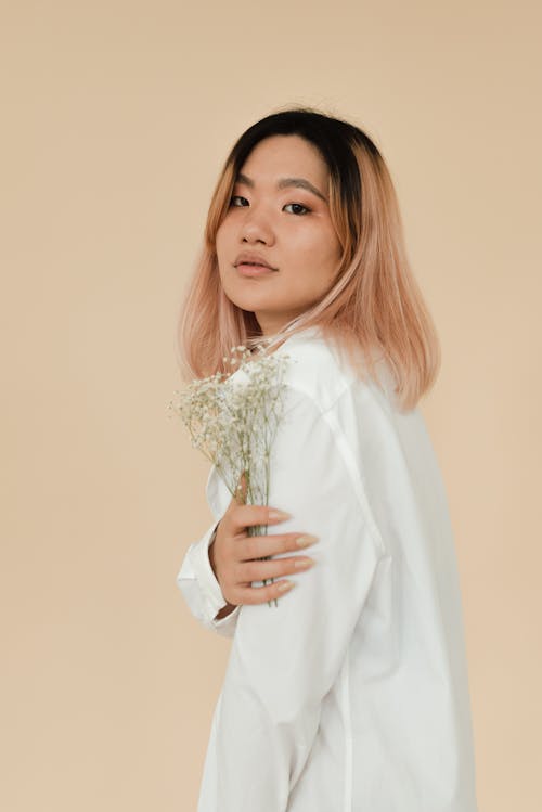 A Pretty Woman in White Long Sleeves Holding Flowers