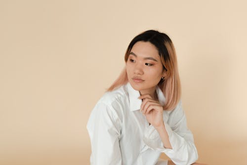 Kostnadsfri bild av asiatisk, beige bakgrund, kvinna