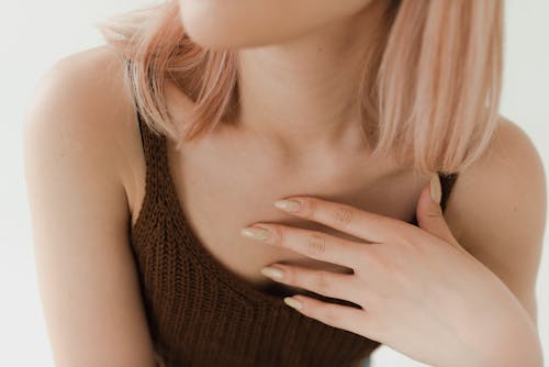 Free A Woman in Brown Knitted Tank Top with Her Hand on Her Chest Stock Photo