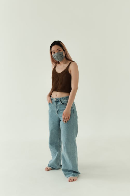 A Woman in Brown Tank Top and Blue Denim Jeans with Face Mask