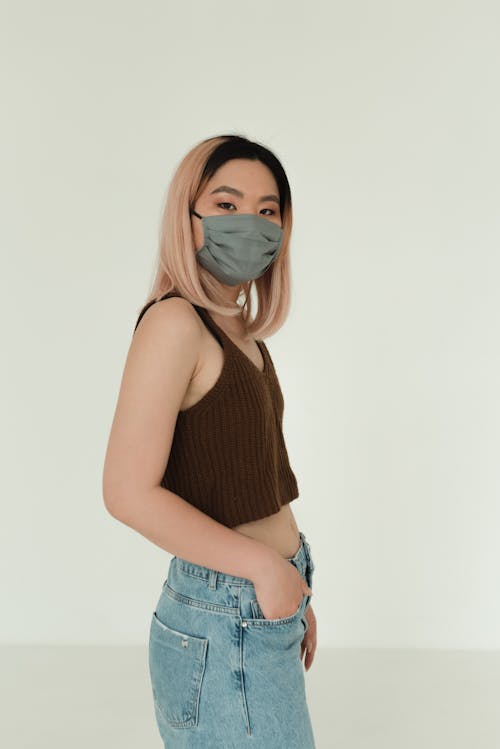 A Woman in Brown Tank Top and Blue Denim Jeans Wearing Face Mask