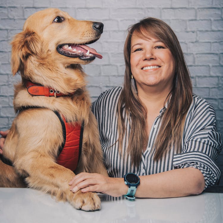 Happy Woman With Dog Sitting At Table