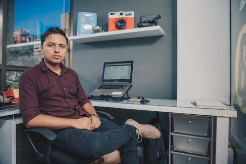 A Man in Brown Button-Up Shirt Sitting on Black Office Rolling Chair