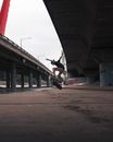 Man in Black Shirt and Blue Denim Jeans Doing Skateboard Stunts Under Bridge