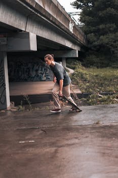 Skater holding a skateboard under a graffiti-covered bridge in Melbourne.