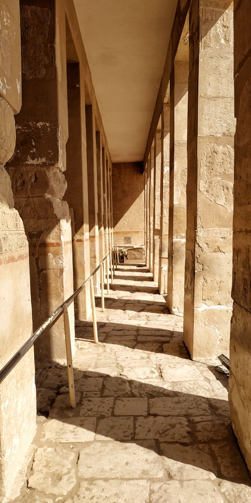 Free Stone corridor with classical columns casting shadows in warm daylight. Stock Photo