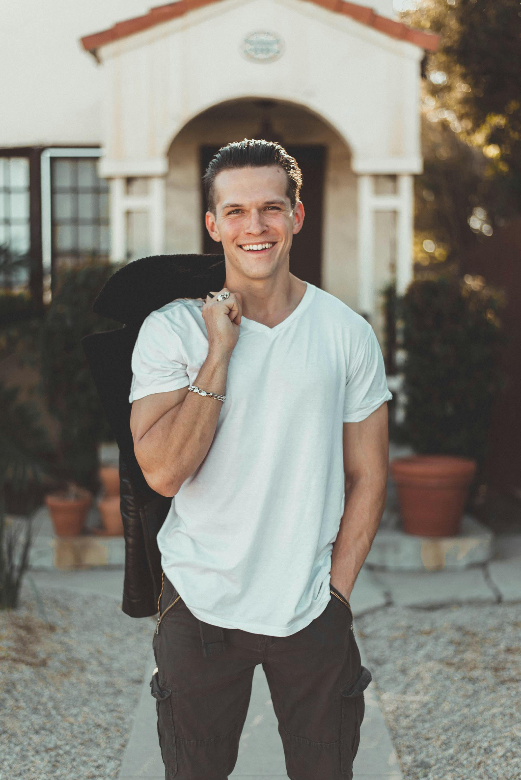 man in white v neck t shirt and black pants