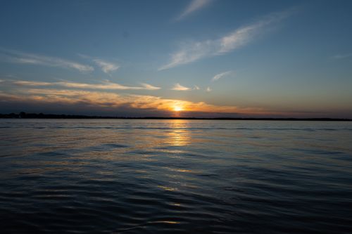 Free A tranquil ocean scene at sunset with beautiful clouds and calm waters reflecting the sky. Stock Photo
