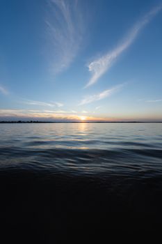 Peaceful sunset reflecting over the calm ocean with a beautiful cloud formation in the sky.