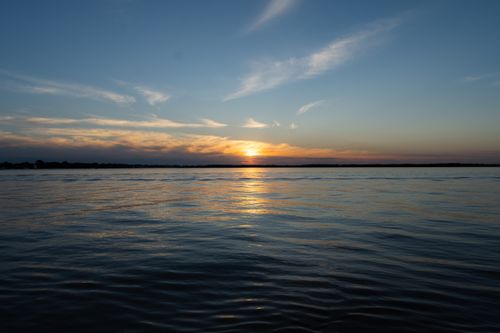 Free Tranquil lake at sunset with golden hour reflections and dramatic sky. Stock Photo