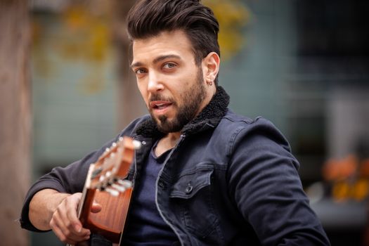 Portrait of a stylish man with a guitar outdoors, exuding a cool vibe.