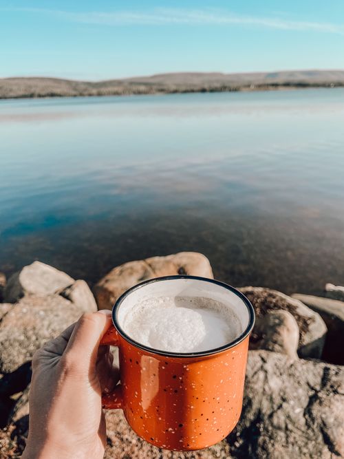 Free Enjoy a peaceful morning with a hot coffee by the calm lakeside in Canada. Stock Photo