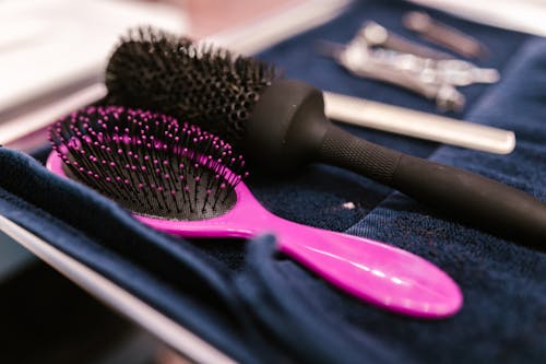 Pink Hairbrush Next to a Black Round Hairbrush