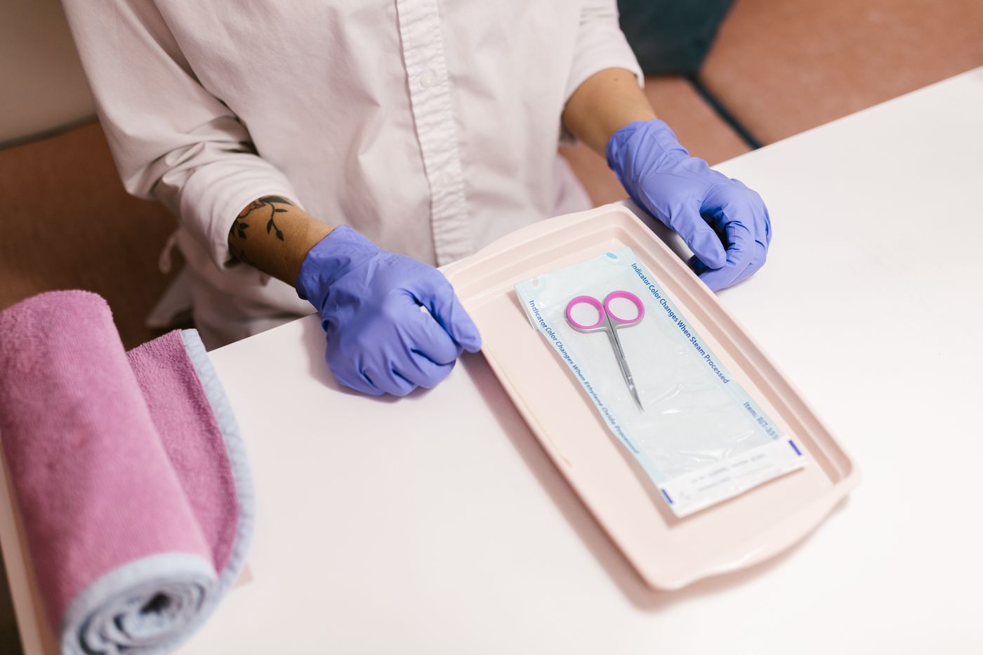 Gloved nail technician preparing metal beauty tools on a clean tray