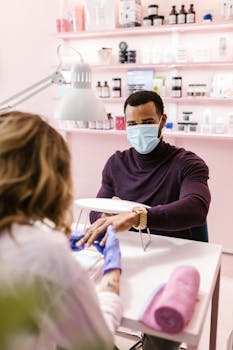 Man wearing a face mask receiving a manicure in a spa setting, emphasizing self-care.