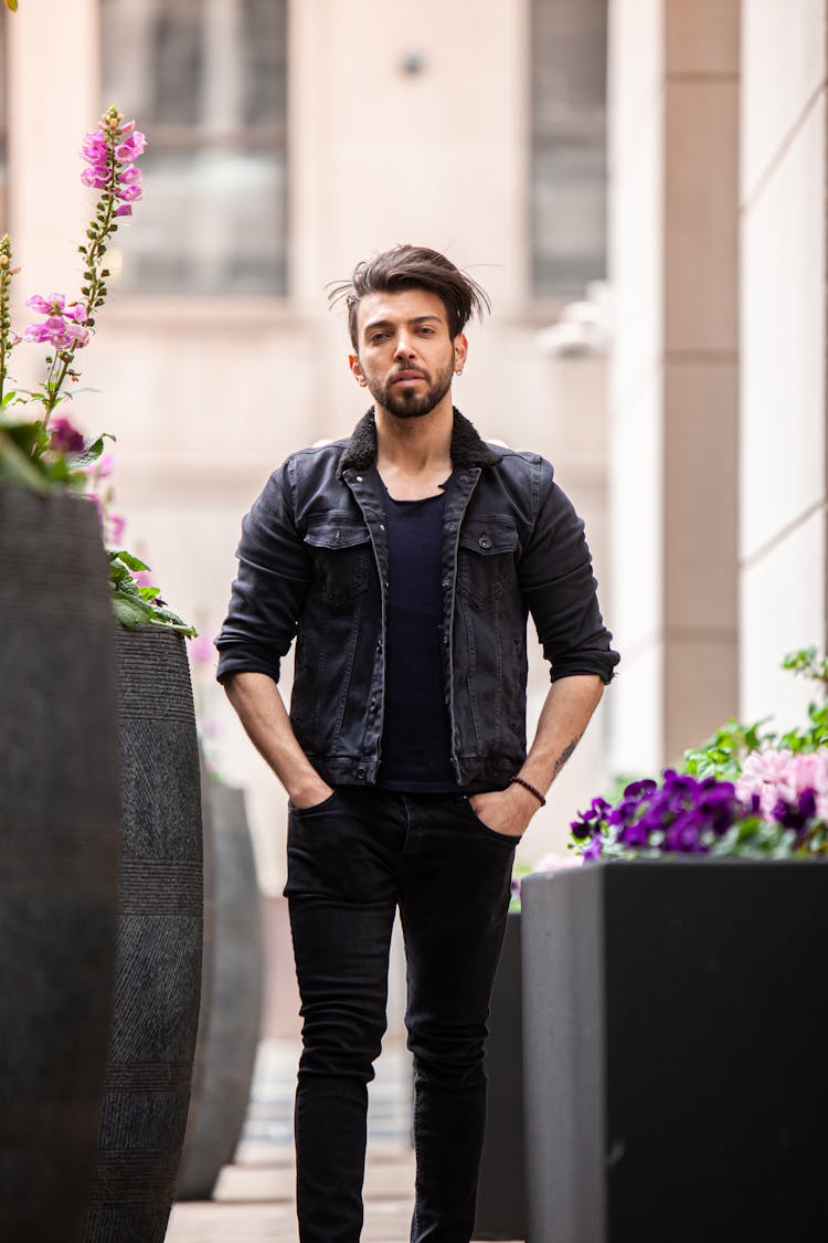 Man In Black Jacket Standing Near Potted Flowers