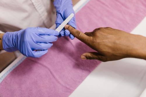 Free Close-up of a manicurist using a nail file on a client's hand during a salon session. Stock Photo