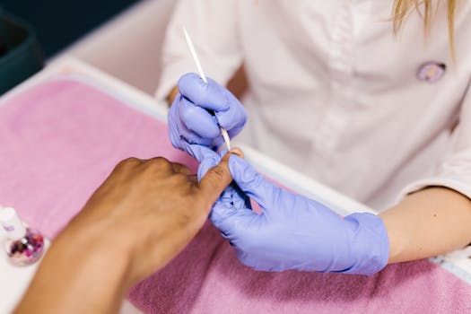 Manicurist performs cuticle care during a manicure session in a salon setting.